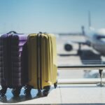 Two suitcases in the airport departure lounge, airplane in the blurred background, summer vacation concept, traveler suitcases in airport terminal waiting area